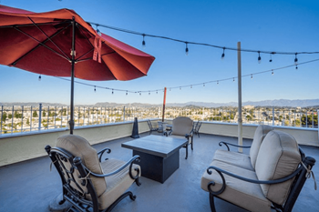A patio with a table, chairs and a red umbrella.